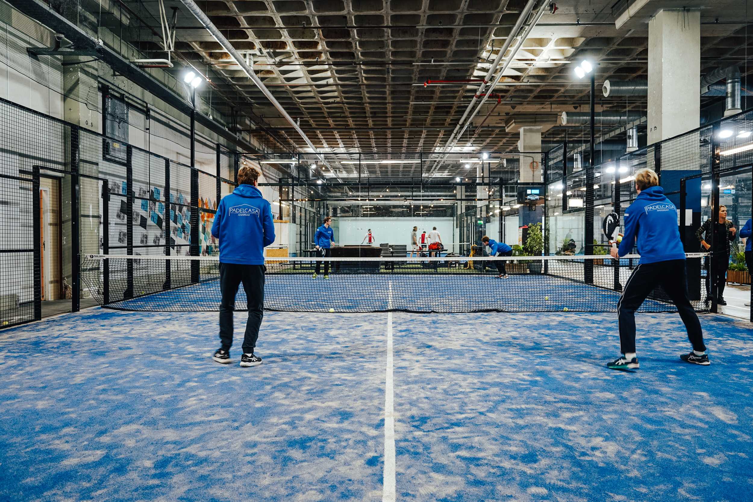 Padelwedstrijd op een blauwe indoorbaan in de hal van B.1