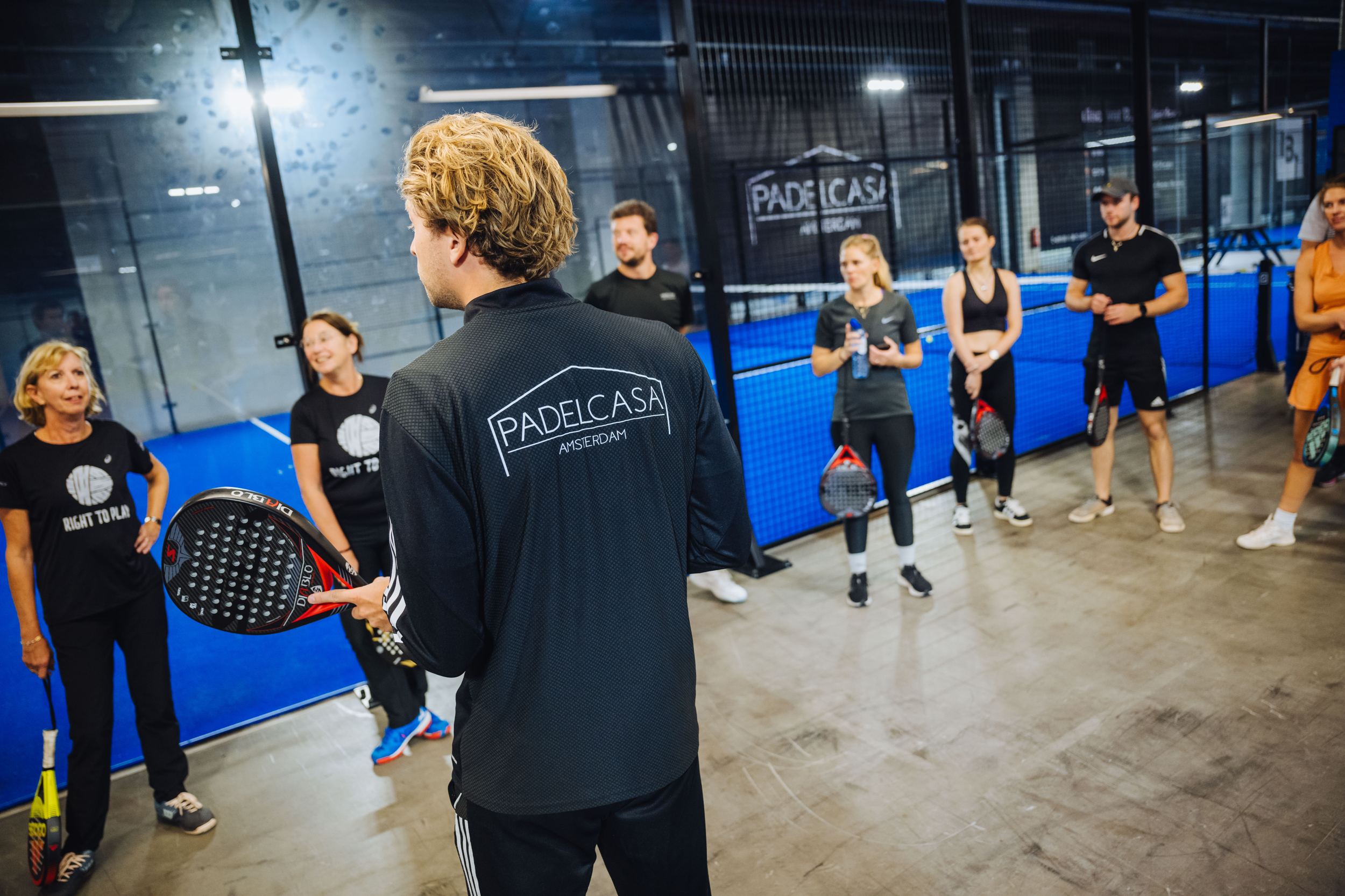 Trainer geeft uitleg aan een groep op de baan