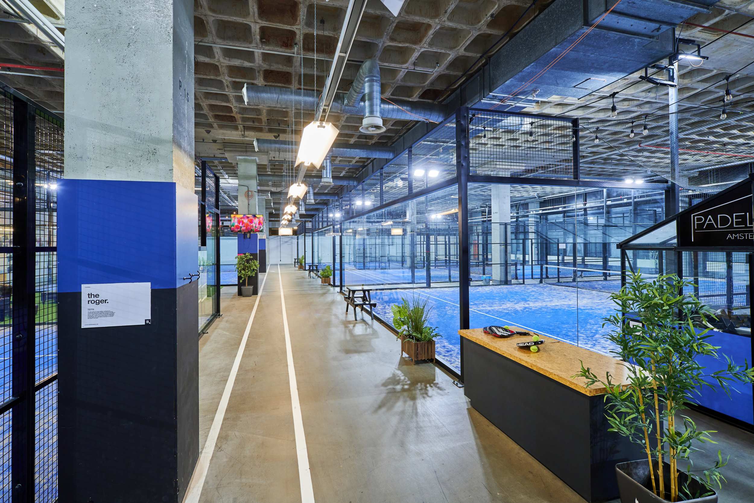 Overzicht van de padelhal met het middenpad tussen de banen